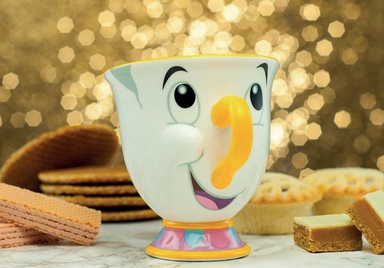 Mug blanc avec le visage de Chip, anse orange et base colorée, entouré de pâtisseries.