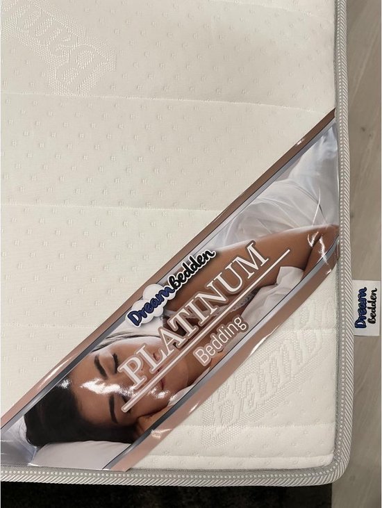 Topdekmatras "Dream Bedden" met label "Platinum Bedding" en slapende vrouw.