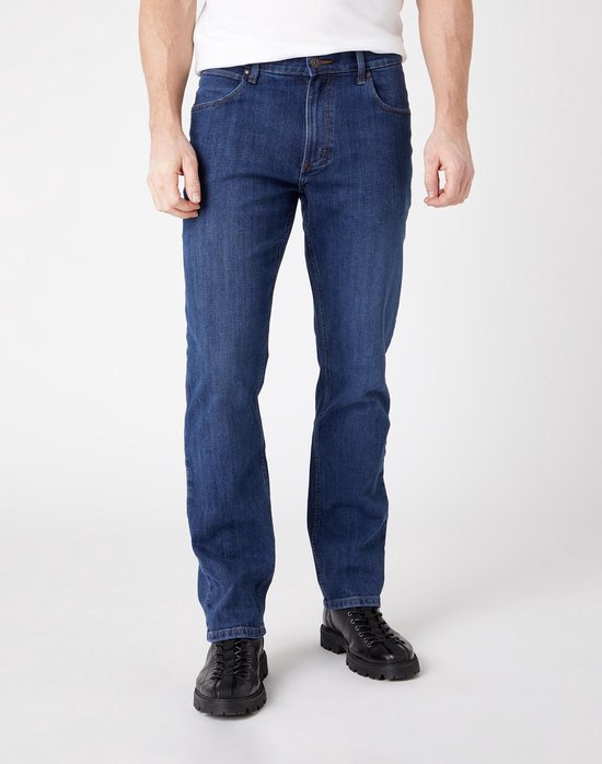 Man met een wit T-shirt en donkerblauwe Wrangler jeans, rechte pasvorm.