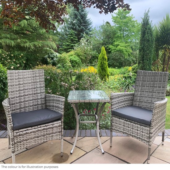Twee grijze rotan stoelen met donkergrijze kussens en een glazen bistrotafeltje, in een tuin.