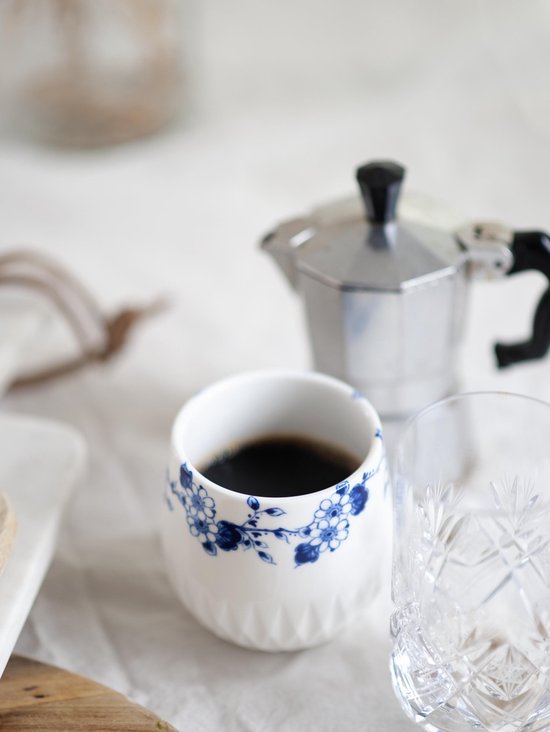 Wit koffiekopje met blauwe bloemenprint en kartelrand.