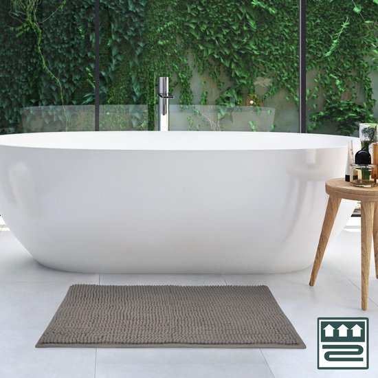 Grijze badmat met bobbelstructuur voor een moderne badkamer met ligbad.