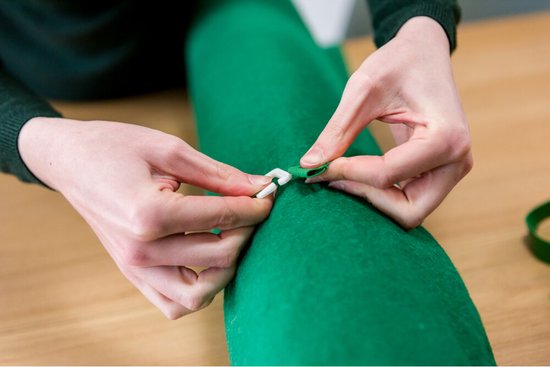 Vrouw sluit groene puzzelmat opgerold af met witte clips.