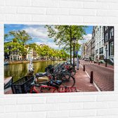 Muursticker - Rij Fiets Geparkeerd langs de Gracht in Amsterdam - 105x70 cm Foto op Muursticker