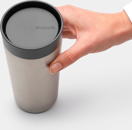 Hand houdt een roestvrijstalen thermosbeker met grijs deksel vast.