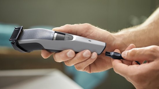 Handen verbinden de USB-oplaadkabel met een zilveren Philips baardtrimmer.