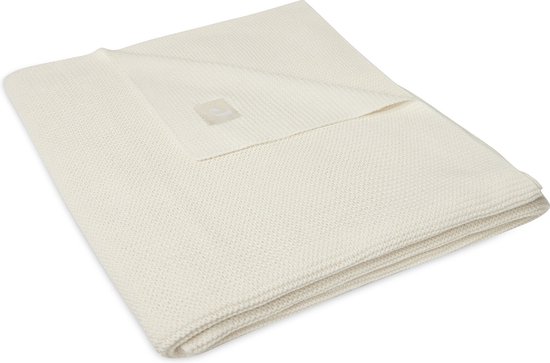 Couverture en maille crème pliée avec une étiquette.