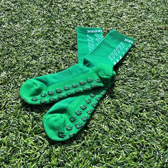 Chaussettes vertes avec crampons noirs sous le pied et rayures blanches.