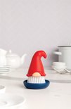 Een afwasborstel in de vorm van een gnome met een rode puntmuts, beige neus en witte borstelharen, staand in een donkerblauwe houder.