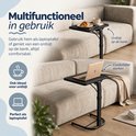 Zwarte multifunctionele laptoptafel gebruikt voor ontbijt en werk bij een bank.