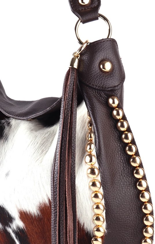 Detail van bruine leren schoudertas met koeienprint, goudkleurige studs en franjes.