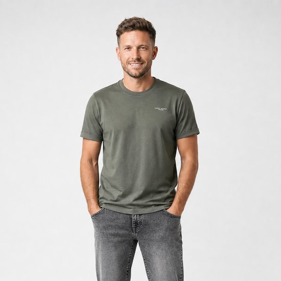 Man met handen in zakken draagt een donkergroen Cars Jeans T-shirt en een grijze spijkerbroek.