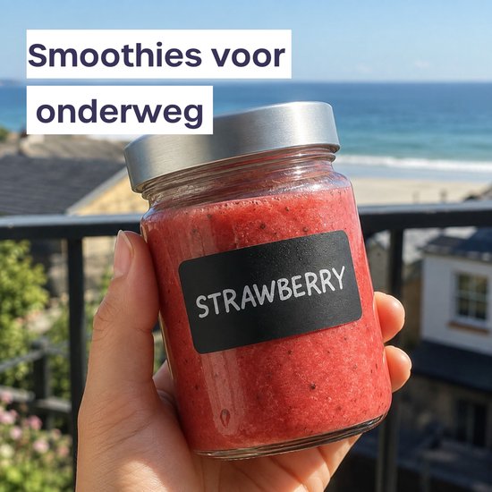 Hand houdt een glazen fles gevuld met aardbeiensmoothie vast, met een zwart 'STRAWBERRY' etiket tegen een strandachtergrond.