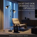 Zwarte staande lamp met twee gouden lampenkappen, verstelbaar. Getoond in een moderne woonkamer.