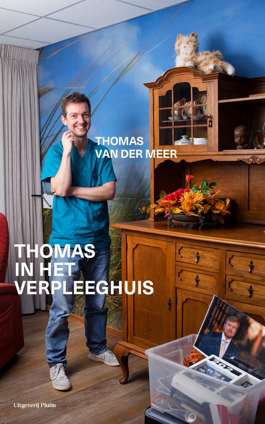 Man in turquoise medische kleding en spijkerbroek staat naast een houten kast. Tekst 'THOMAS VAN DER MEER' en 'THOMAS IN HET VERPLEEGHUIS'.