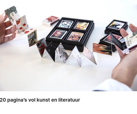 Handen houden een lang, uitgevouwen accordeonboekje vast naast een doos met meerdere kleine boekjes.