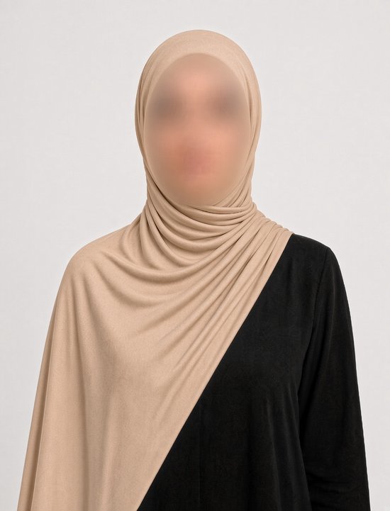 Model draagt een beige jersey hijab over een zwart kledingstuk, zachte stof met plooien.