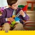 Jongen met een kleurrijke LEGO gitaar in de handen, gemaakt van rood, oranje, geel, groen, blauw en roze stenen.