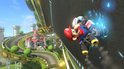 Mario racet op een kartbaan met een kasteel en groene heuvels op de achtergrond, de baan is schuin.