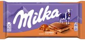 Paarse Milka reep met karamel, bergen op de achtergrond, een koe en een doorgesneden reep.