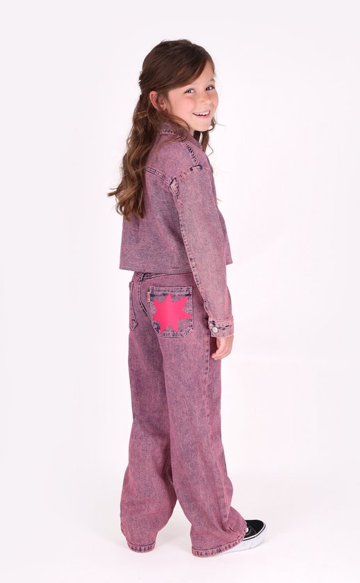 Meisje in een roze denim set, met een roze ster op de achterzak van de wijde spijkerbroek.