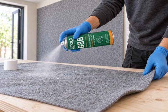 Handen met blauwe handschoenen spuiten Gekko G26 lijm op grijs viltmateriaal.