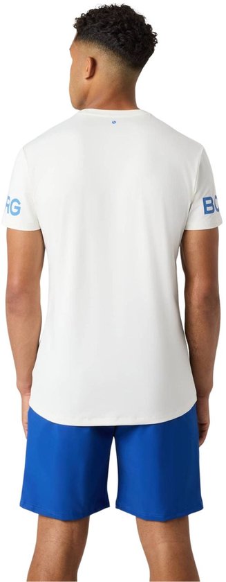 Man in wit sportshirt met blauwe tekst op de mouwen, en een blauwe short.