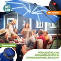 Donkerblauwe zweefparasol met LED-verlichting, solar-bediend, boven een buiten diner.