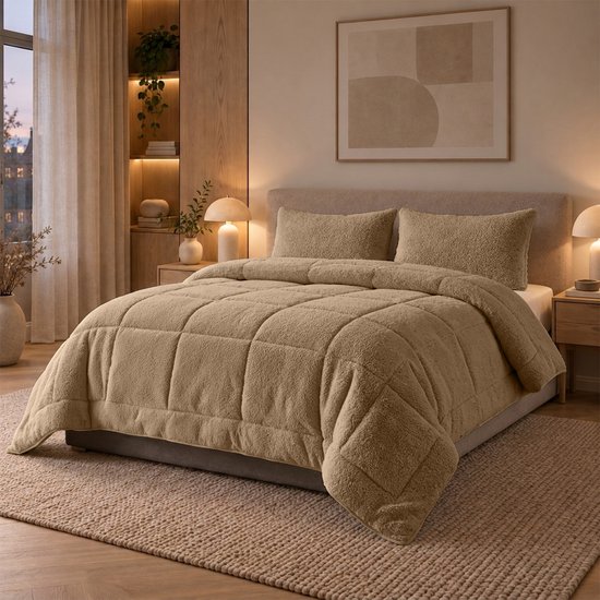 Een taupe teddy dekbed met ruitpatroon ligt op een bed met twee teddy kussens.