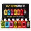 Crazy Bastard 7 Sauce Set: zeven flessen saus, groen, blauw, roze, geel, oranje, rood en donkerrood, naast de zwarte doos.