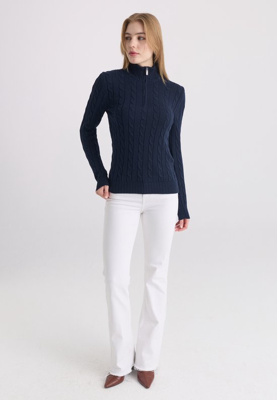 Donkerblauwe kabeltrui met ritskraag, gedragen door een model met witte broek.