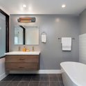 Grijze 1200W badkamerkachel gemonteerd boven de wastafel in een moderne badkamer met oranje gloeiende verwarmingselementen.