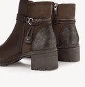 Detailopname van bruine Tamaris enkellaarsjes met gevlochten riempjes, metalen accenten en een glinsterende hiel.