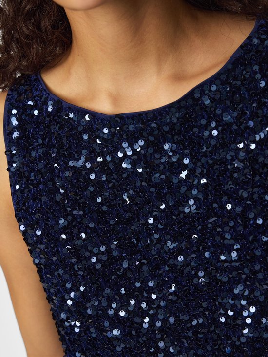 Close-up van het décolleté van een vrouw in een donkerblauw mouwloos topje met pailletten.
