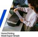 Vrouw met lichtroze trui en beige broek plaatst papier in een HP DeskJet 2920 printer.