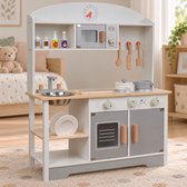 Grijswitte houten speelkeuken met magnetron, oven, metalen spoelbak en speelgoedflessen.