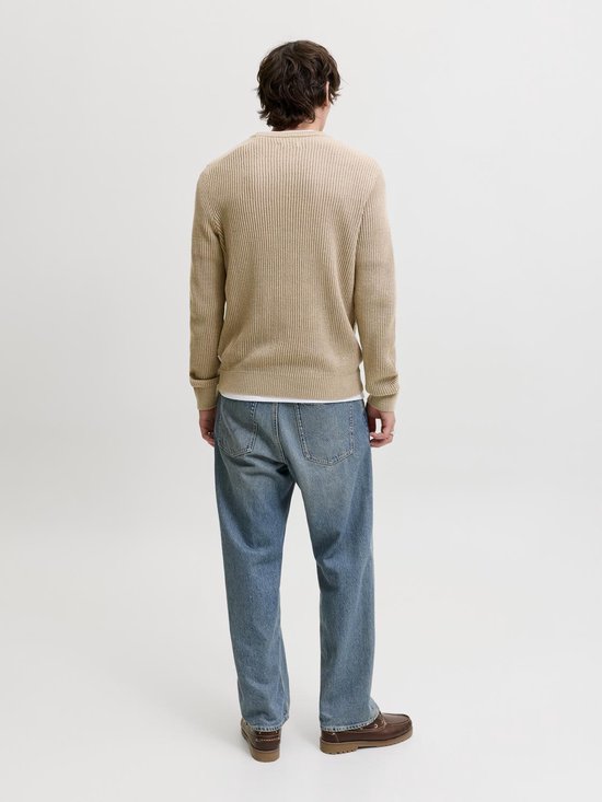 Man met beige gebreide trui met ribbels en blauwe jeans, model staat naar achteren.