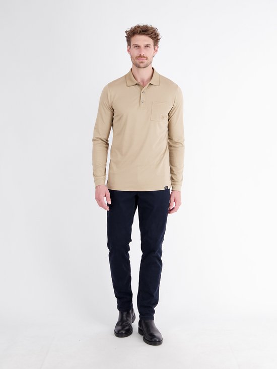 Man draagt beige poloshirt met lange mouwen, donkerblauwe broek en zwarte laarzen.