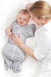 Baby in een grijs gestreepte slaapzak met witte strepen, liggend naast een vrouw.