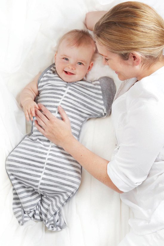 Baby in een grijs gestreepte slaapzak met witte strepen, liggend naast een vrouw.