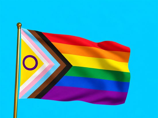 Wapperende intersekse-progressvlag aan een gouden mast tegen een blauwe achtergrond.
