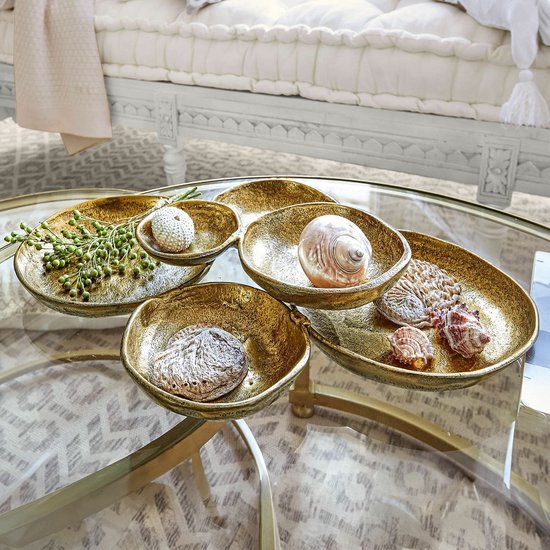 Set van vier goudkleurige schalen met een ruwe, antieke textuur, gevuld met decoratieve schelpen en takjes op een glazen tafel.