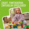 Meisje speelt met kleurrijke, doorschijnende bouwstenen in jungle-thema, waaronder palmbomen en dieren. Zacht, fantasierijk, zintuiglijk speelgoed!