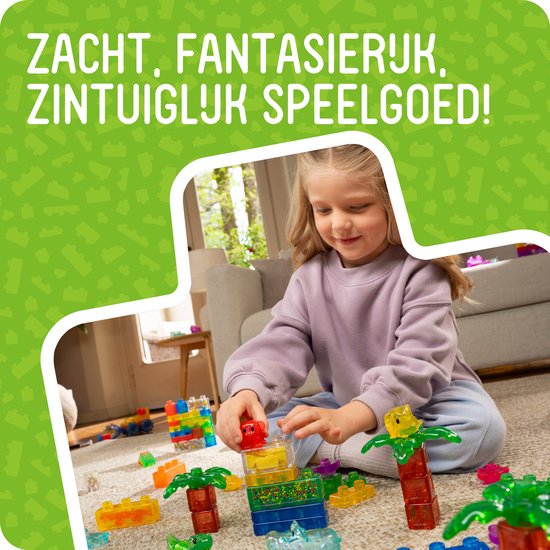 Meisje speelt met kleurrijke, doorschijnende bouwstenen in jungle-thema, waaronder palmbomen en dieren. Zacht, fantasierijk, zintuiglijk speelgoed!