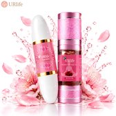 Yoni Stick en Yoni Essentiële Olie in glanzende roze verpakking, omringd door roze bloesems en waterdruppels.