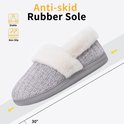 Grijze pantoffel met witte pluche rand op een helling, toont antislip rubberen zool en stabiele grip.