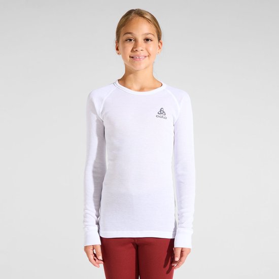 Meisje draagt een wit Odlo thermoshirt met lange mouwen en rode legging tegen een grijze achtergrond.