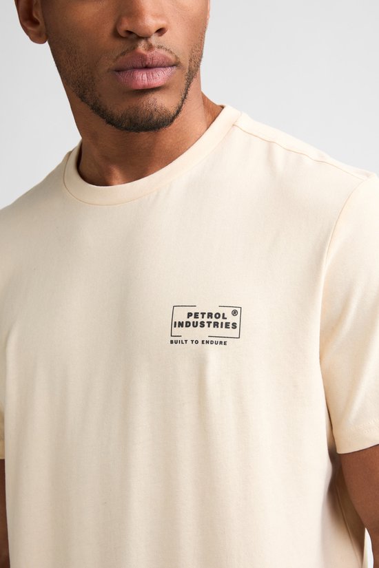 Close-up van een crème T-shirt met logo 'Petrol Industries Built to Endure'.