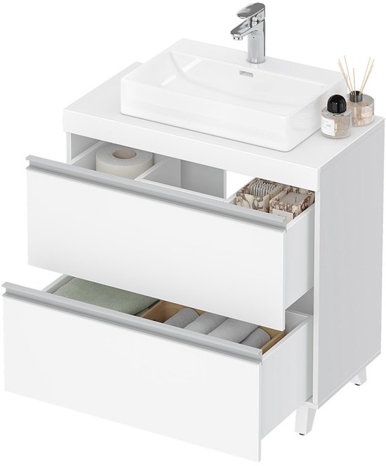 Witte wastafelonderkast met twee open laden, gevuld met toiletpapier, handdoeken en zeepjes.