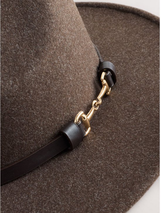 Detail van een bruine vilten fedora met een zwarte band en gouden bit.